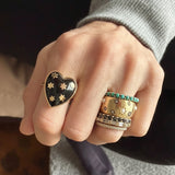 Hand wearing multiple rings with star designs on a neutral background
